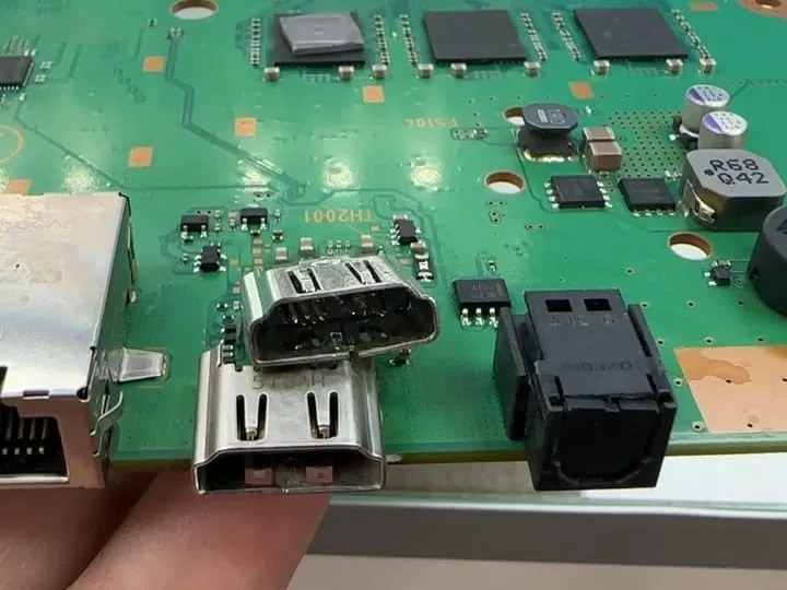 Two PS4 HDMI ports side by side, a removed port held in front of the console motherboard